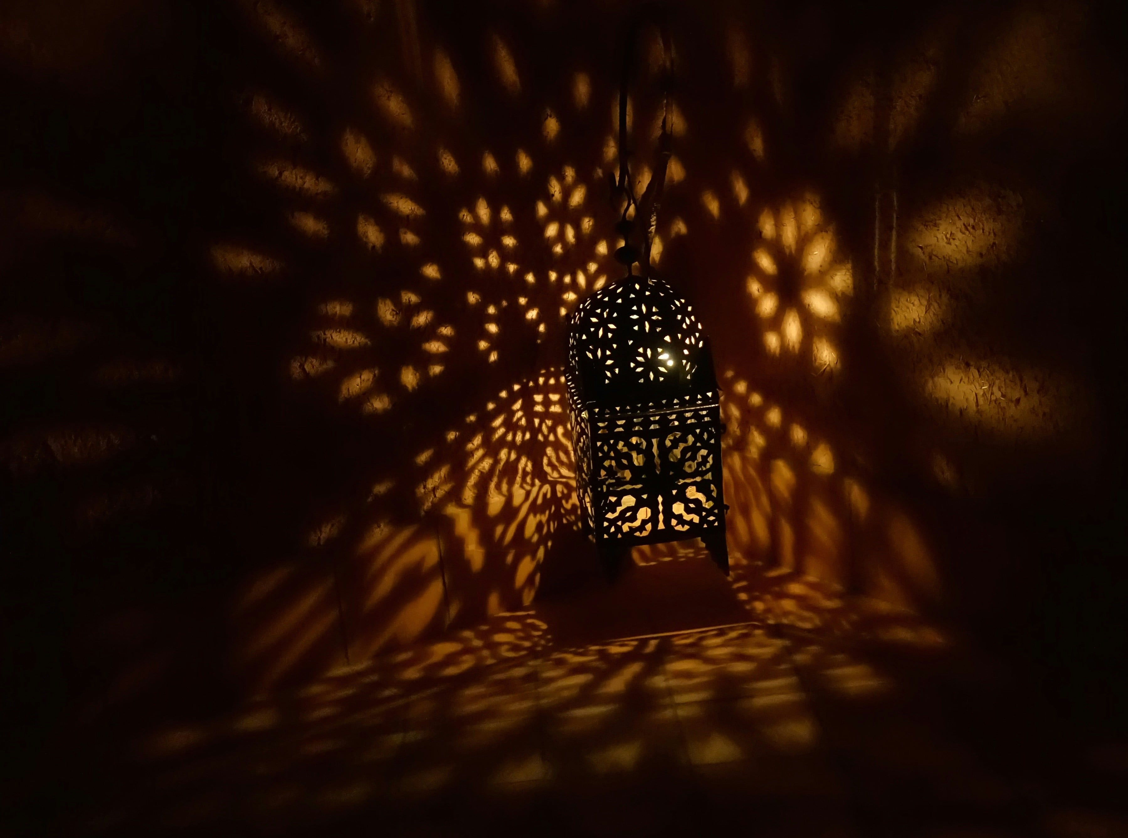 A pierced lantern casting patterns of light across a dark room, Morocco