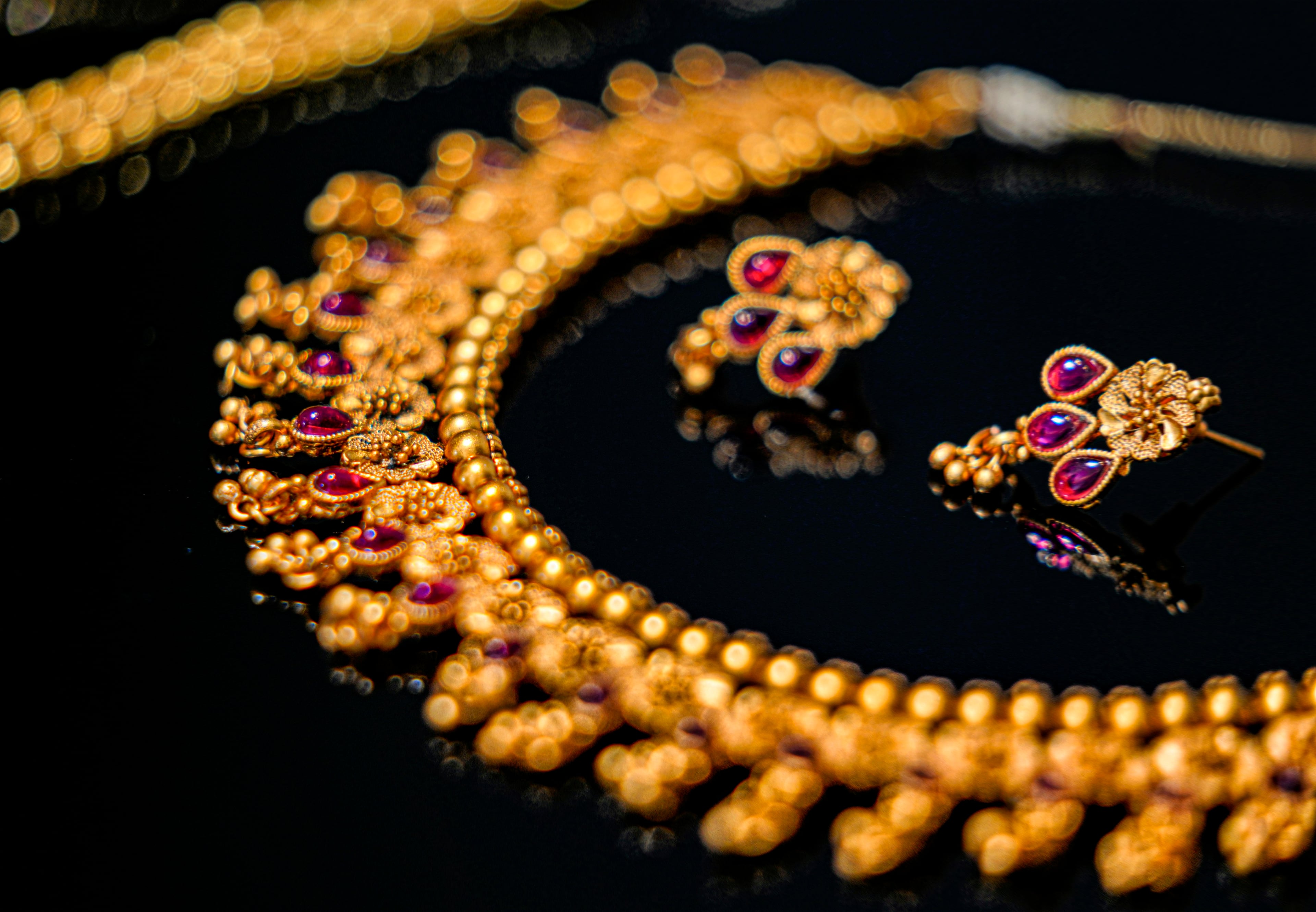 A gold necklace and earrings set with red stones